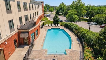 Une piscine avec, en arrière-plan, un bâtiment en briques aux couleurs beige.