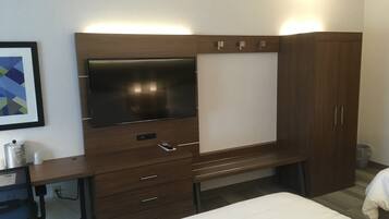 A hotel room with a bed, a desk with a chair, a TV, and a wardrobe.