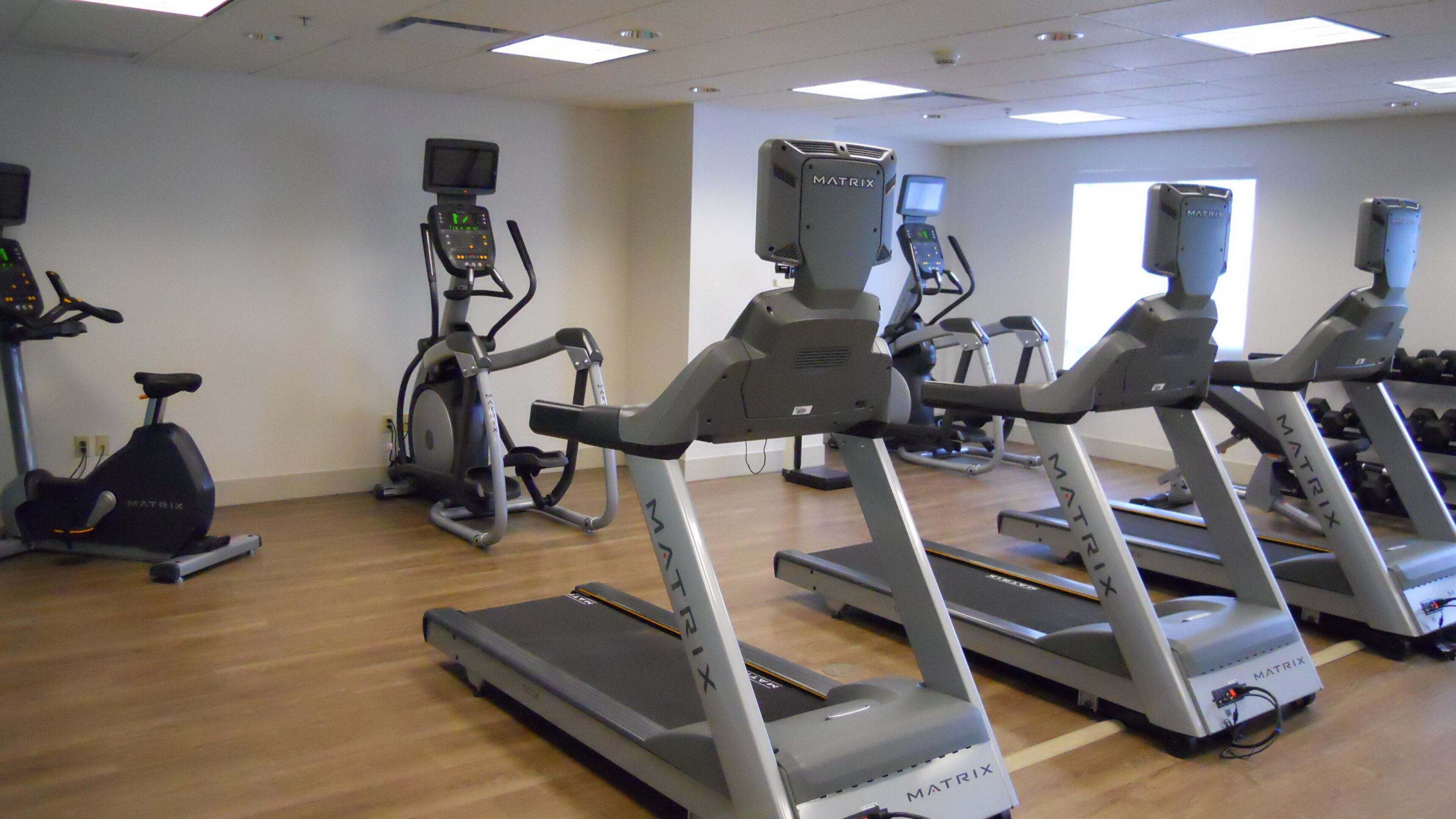 A gym with multiple treadmills, stationary bikes, and elliptical machines.