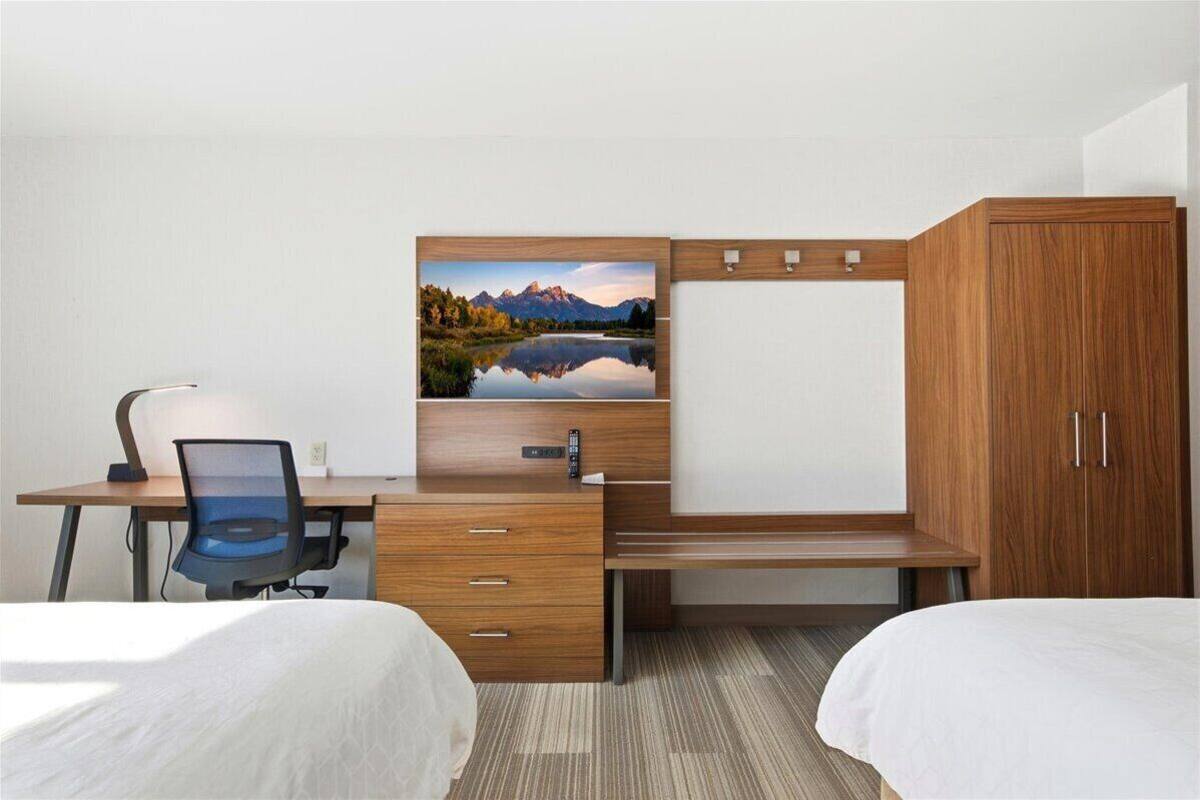 Een hotelkamer met een houten bureau, een stoel, een bed en een kledingkast.