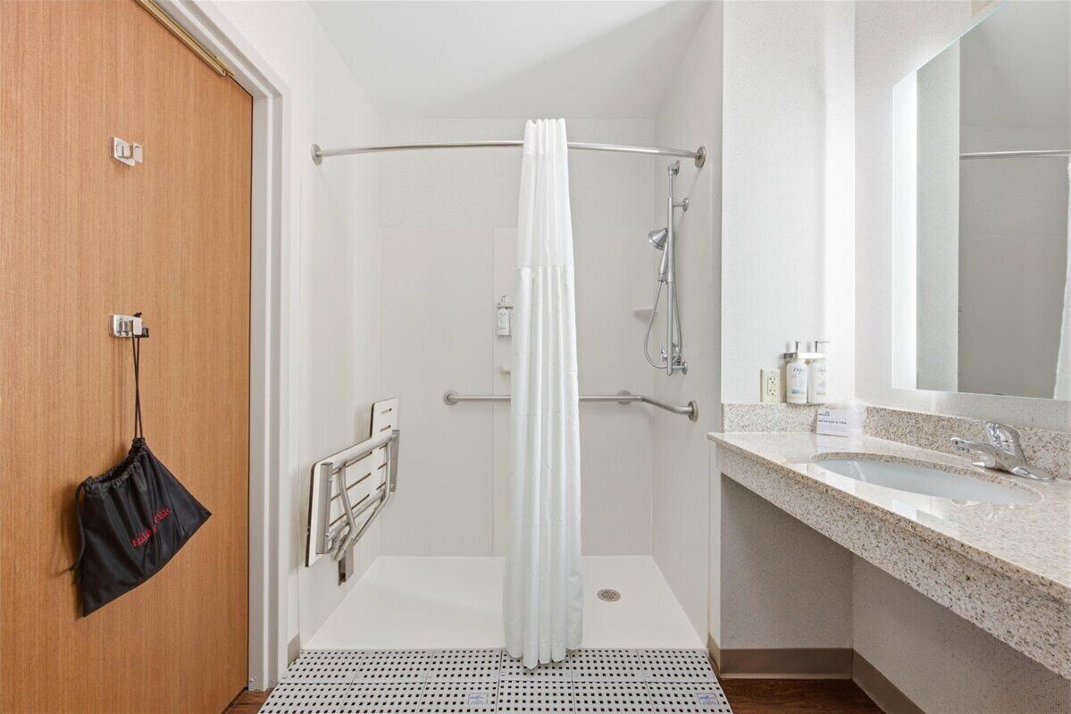 A modern bathroom with a shower, a sink, and a mirror.