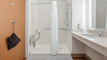 A modern bathroom with a shower, a sink, and a mirror.
