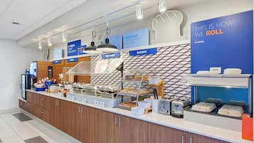 A breakfast buffet area with labeled sections for hot food, bakery, and cereal.