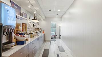 A modern kitchen area with a breakfast bar, a coffee machine, and various food containers.