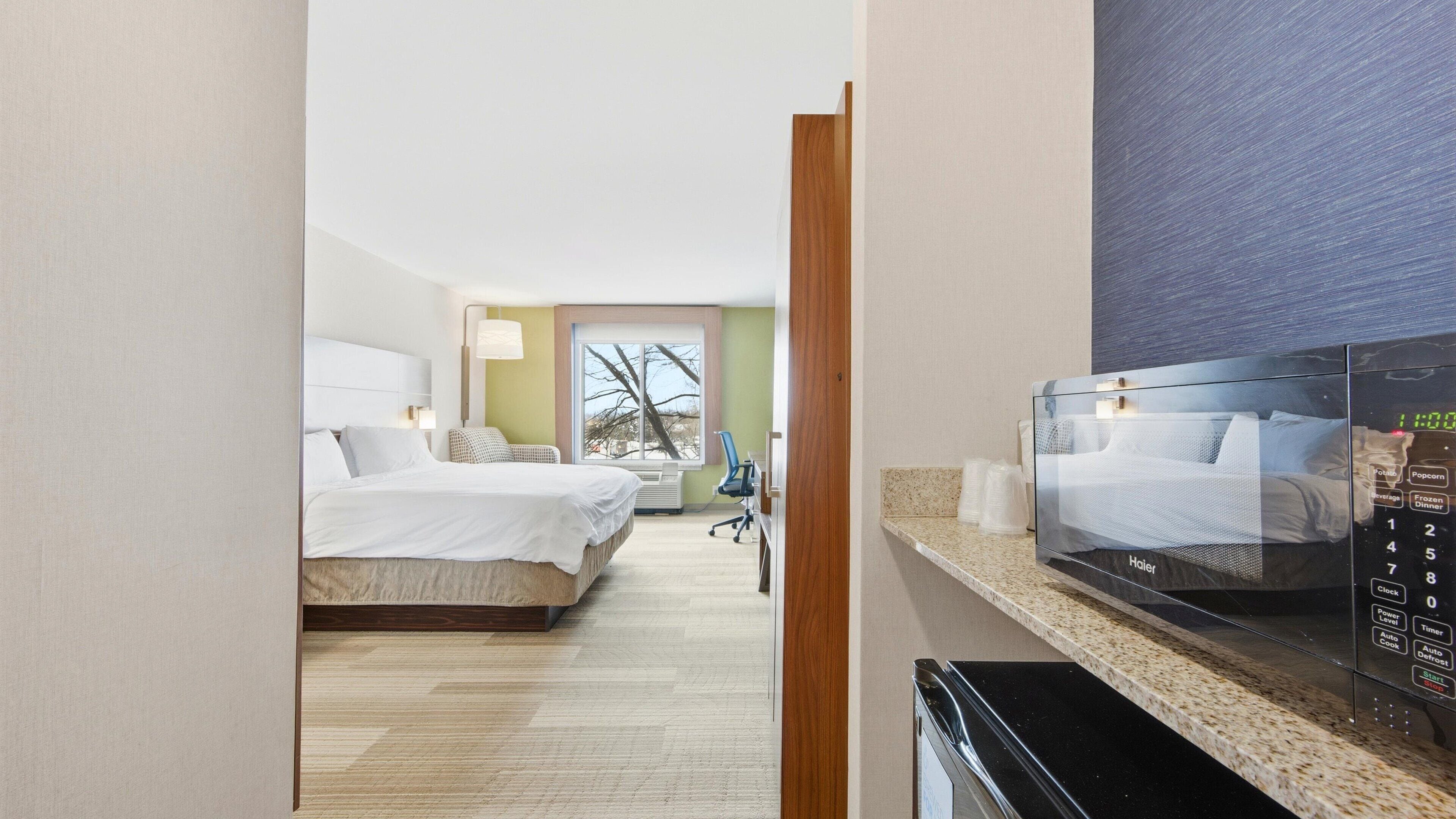 Une chambre d’hôtel avec un lit, un bureau et un four à micro-ondes.