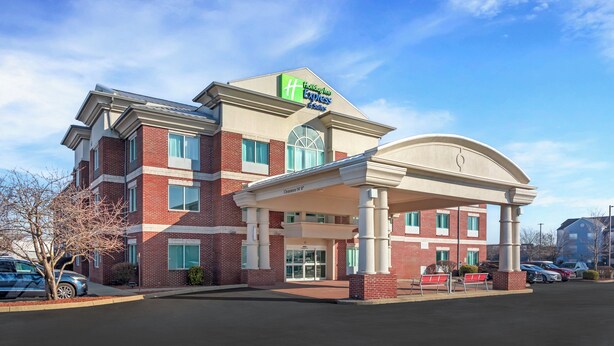 Un hôtel Holiday Inn Express avec une façade en briques, une entrée couverte et un parking.