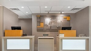 Un espace d’accueil comprenant deux comptoirs de réception, un panneau d’information central et un petit comptoir.