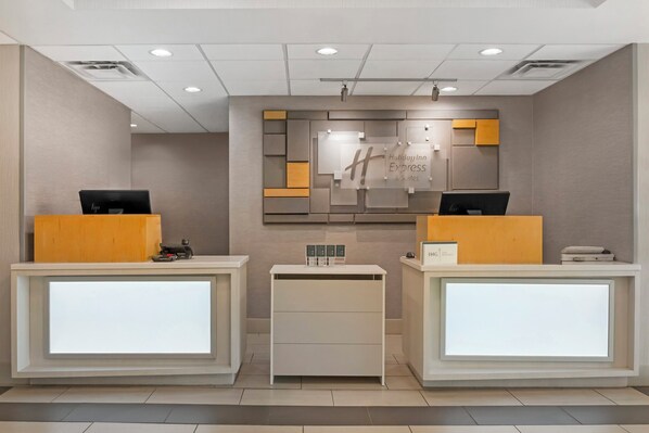 A reception area with two reception desks, a central information board, and a small counter. - Holiday Inn Express Hotel & Suites Hillview by IHG (Louisville)