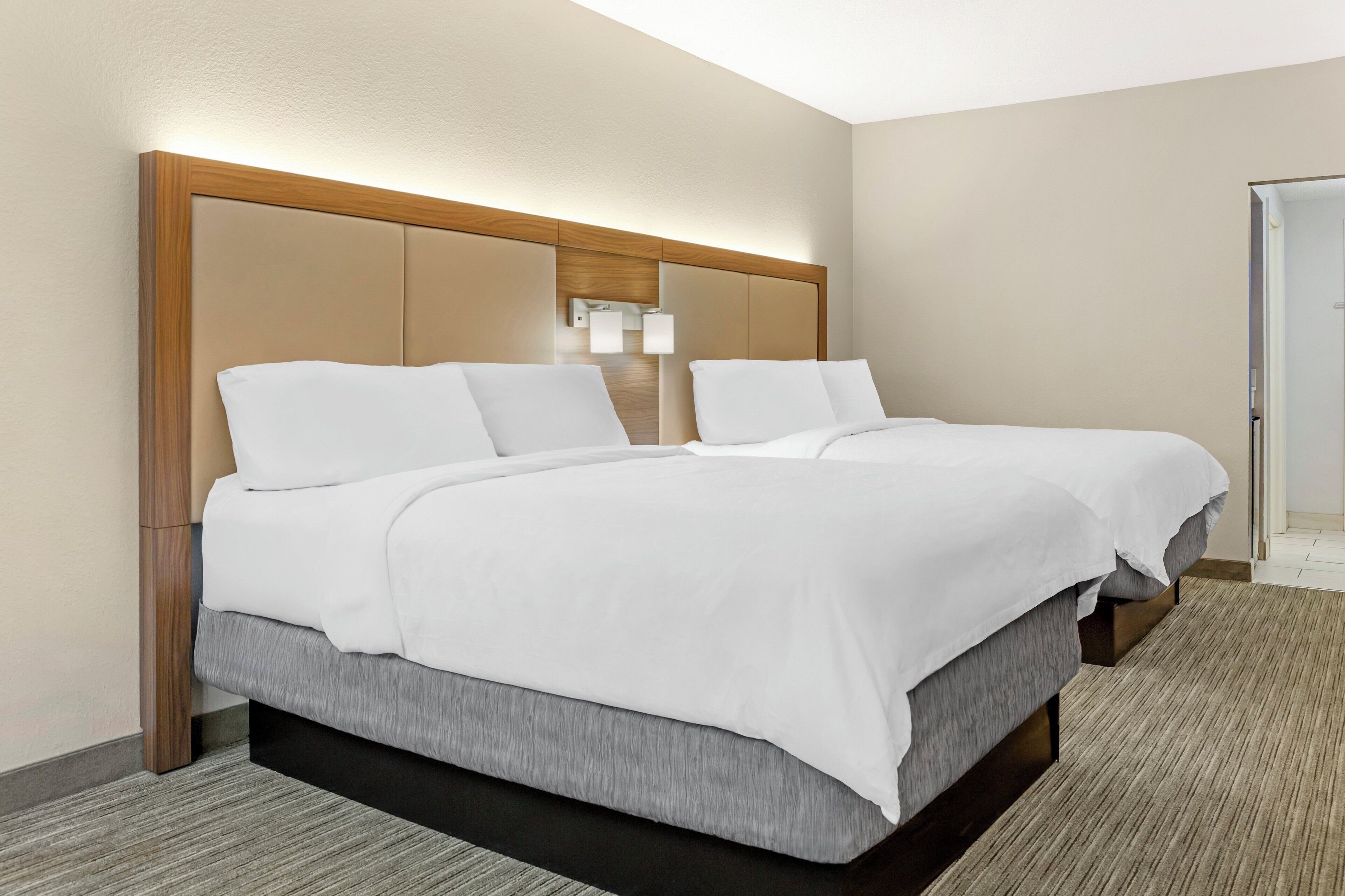 A hotel room with a large bed, a wooden headboard, and a carpeted floor.
