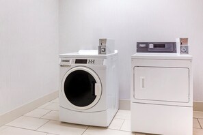 A laundry room with a front-loading washing machine and a stacked dryer. - Holiday Inn Express Hotel & Suites Hillview by IHG (Louisville)