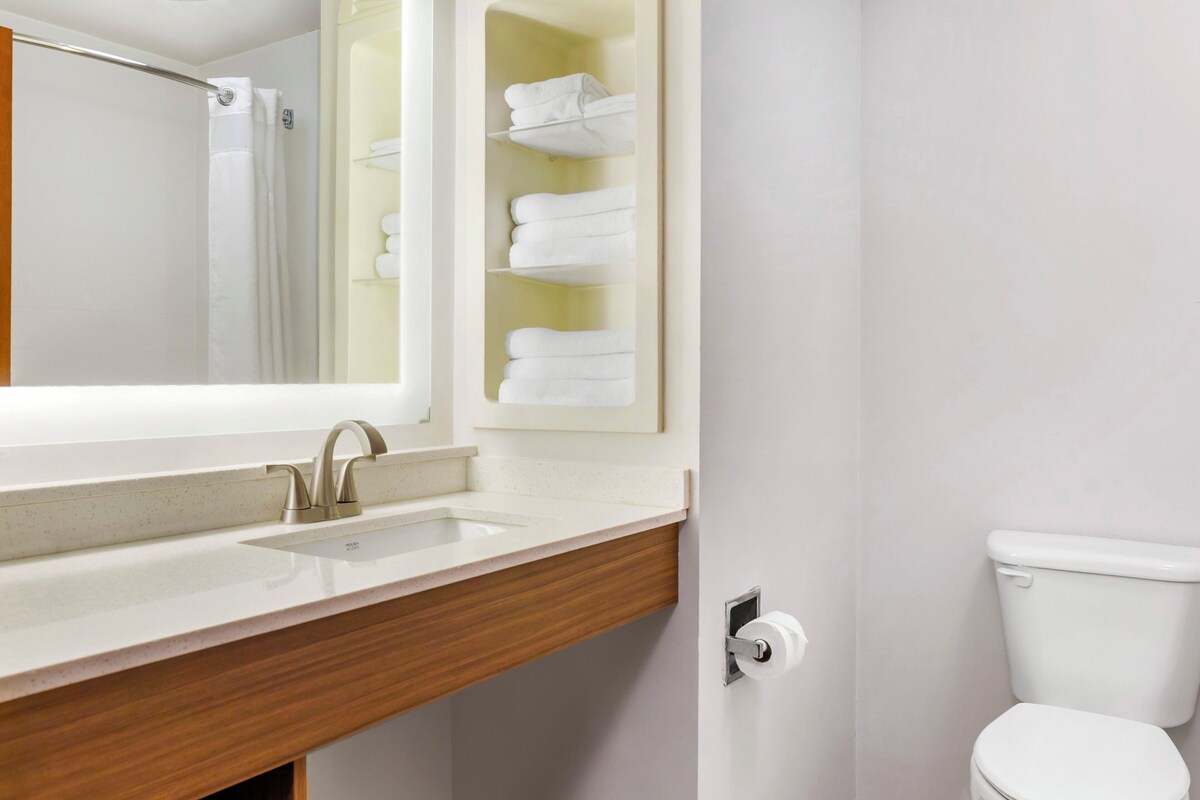 A bathroom with a sink, mirror, towel rack, and toilet.