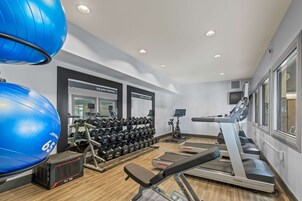 Un gimnasio con equipo de ejercicio, que incluye una cinta de correr, pesas y pelotas de ejercicio.