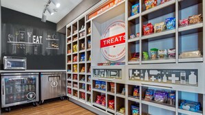 A snack and drink vending area with a chalkboard wall displaying the word "EAT" and a sign indicating a treats section. - Hampton Inn & Suites Greeley (Greeley)