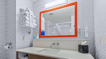 Une salle de bain moderne avec un grand miroir, un porte-serviettes, un lavabo et un sèche-mains.