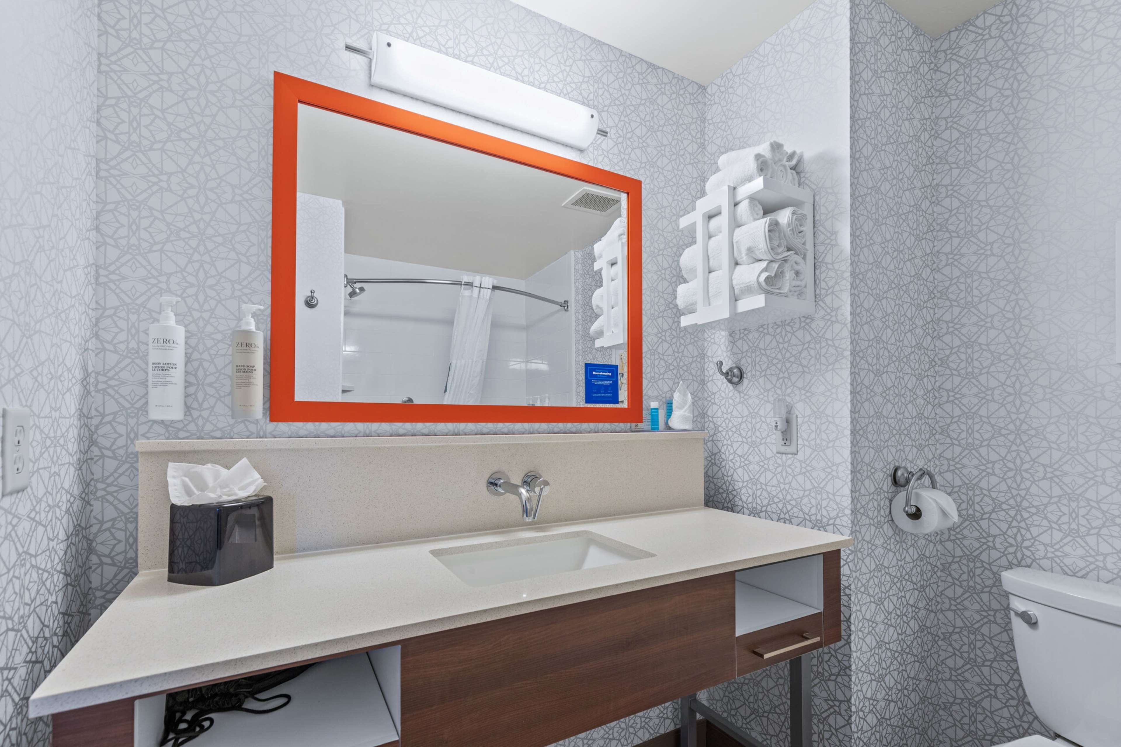 A modern bathroom with a large mirror, a sink, and a toilet.