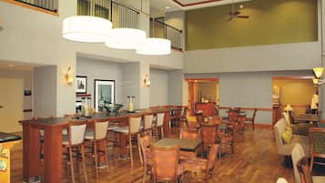 A spacious hotel lobby with high ceilings, multiple dining areas, and a visible staircase.