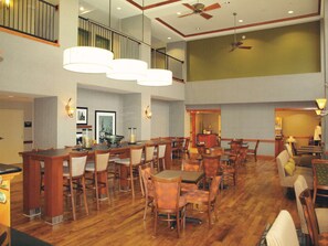 A spacious hotel lobby with high ceilings, multiple dining areas, and a visible staircase. - Hampton Inn Clinton (Clinton)