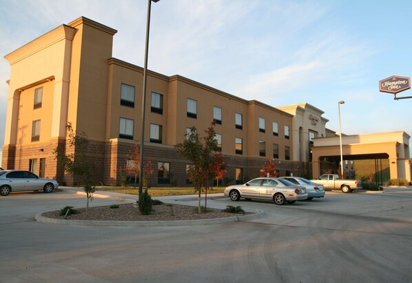 A Hampton Inn hotel with a parking lot, a few cars, and a clear sky. - Hampton Inn Clinton (Clinton)