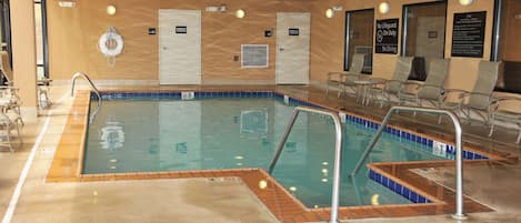 Una piscina con borde de azulejos, una estación de salvavidas y un letrero que indica que no hay salvavidas de servicio.