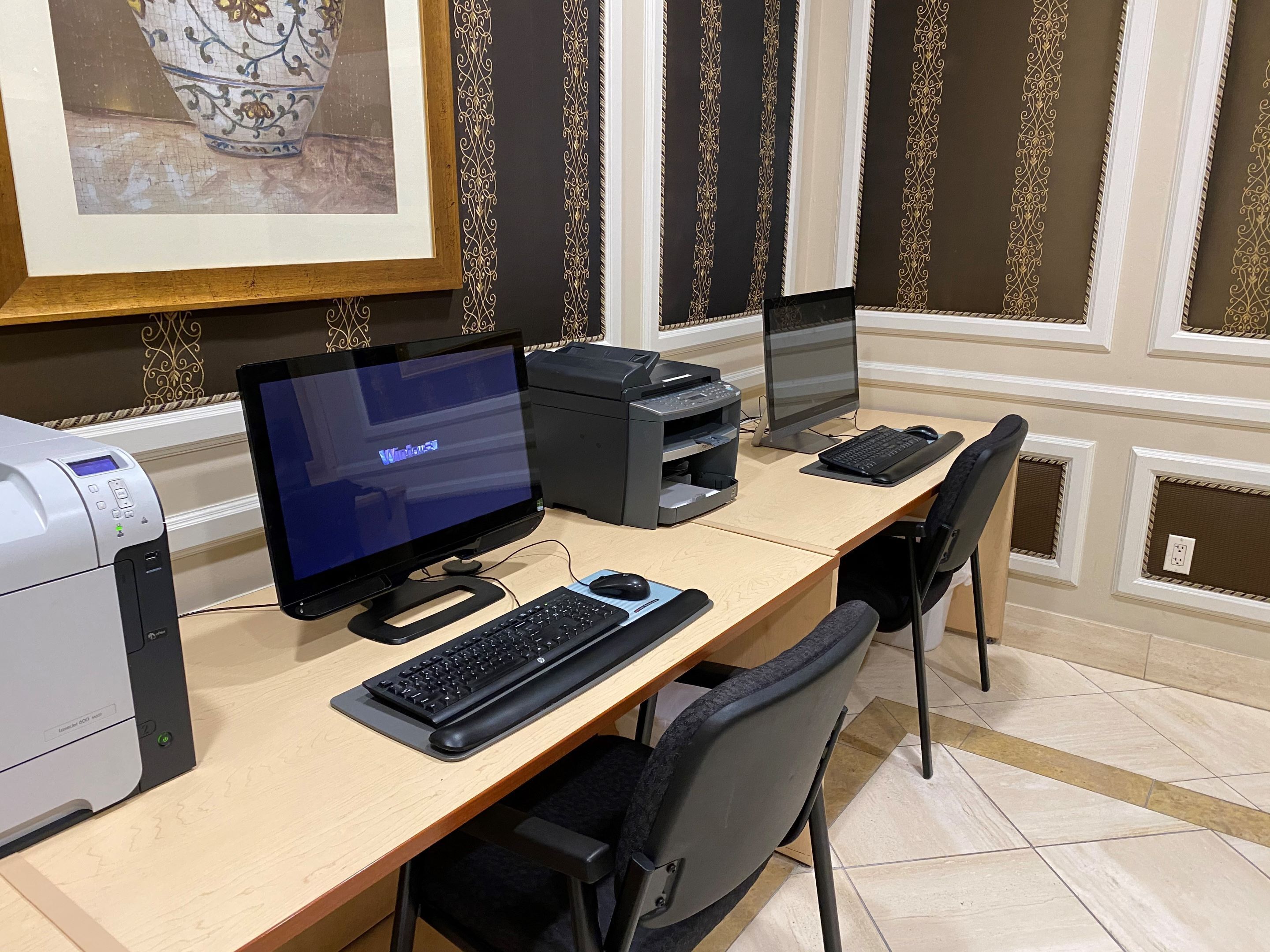 Una oficina bien equipada con computadora de escritorio, impresora y monitor.