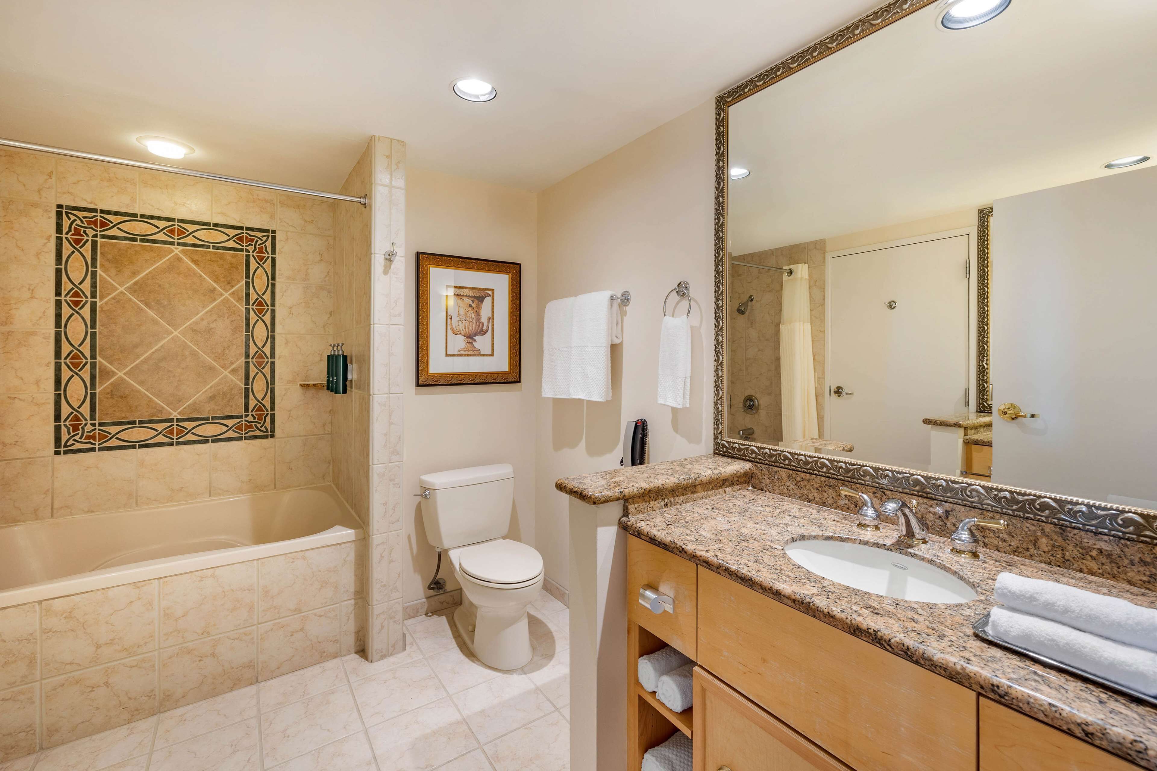 A bathroom with a bathtub, toilet, sink, and a large mirror.