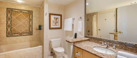 A bathroom with a bathtub, toilet, sink, and a large mirror.