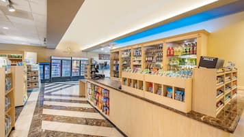 Una farmacia con mostrador de autopago, secciones refrigeradas y una cafetería al fondo.