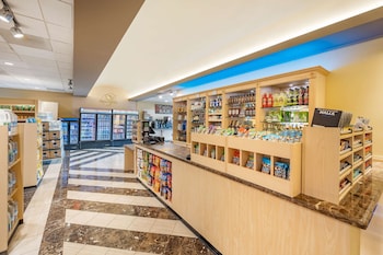 A modern hotel reception area with a white reception desk, a large framed artwork, and a seating area with chairs. at Hilton Vacation Club Polo Towers Las Vegas