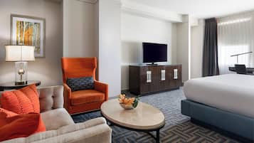 Une chambre d’hôtel comprenant un lit, un canapé, un fauteuil, une table basse, une télévision et un meuble.