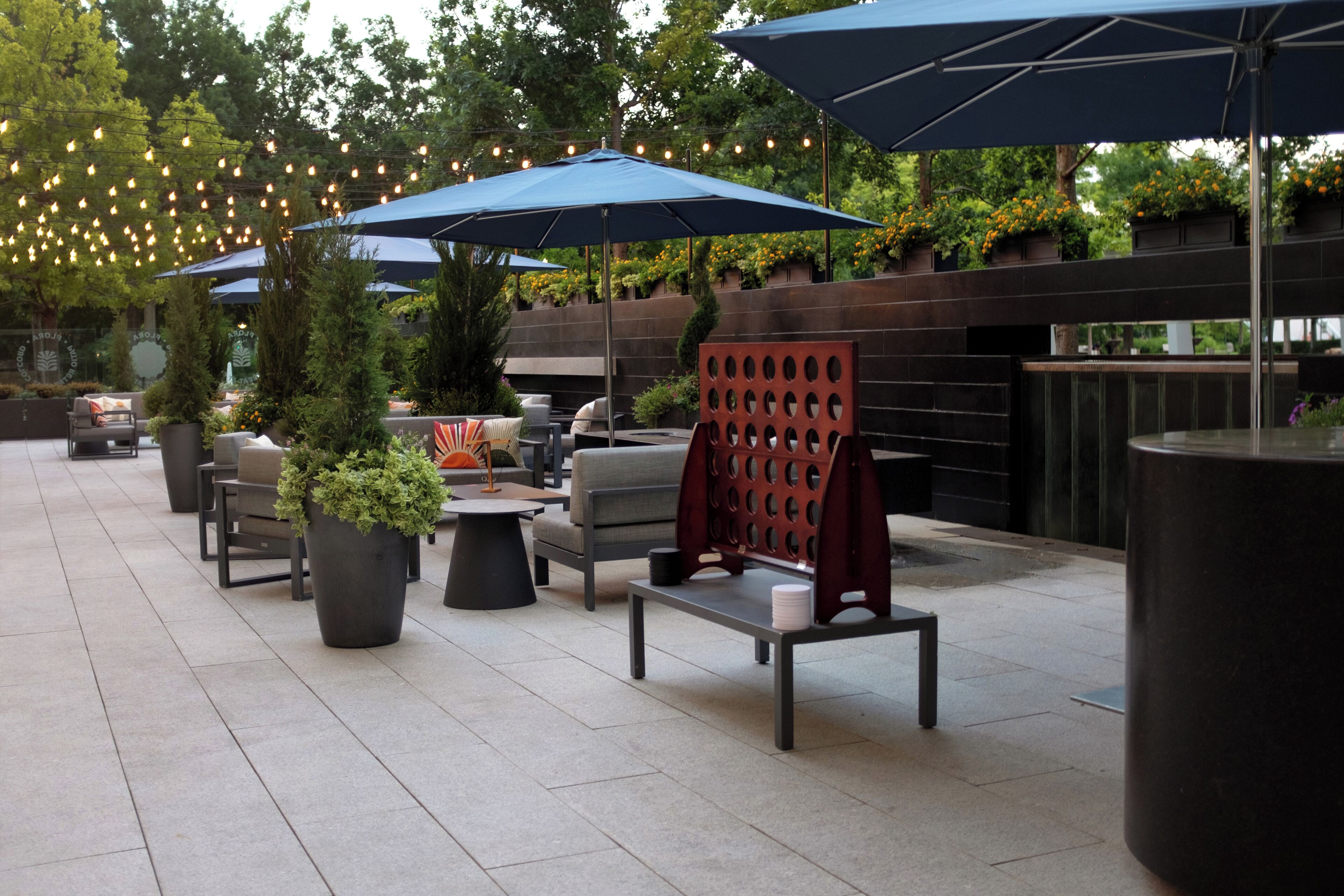 An outdoor patio area with seating arrangements, umbrellas, and potted plants.