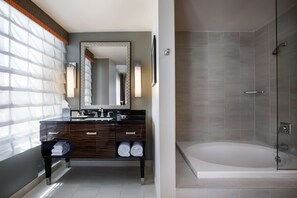 Une salle de bain moderne avec un meuble-lavabo en bois foncé, un grand miroir et une douche à parois de verre.