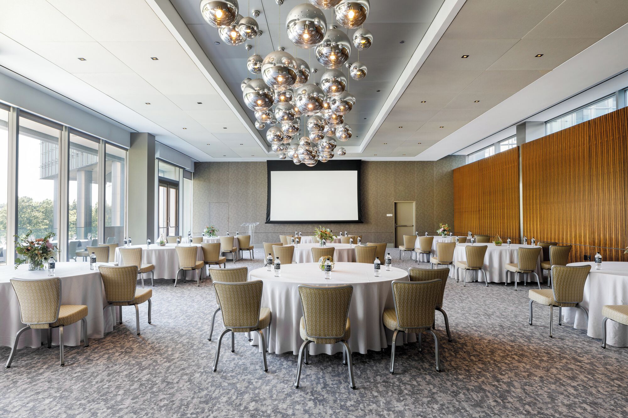 A conference room with round tables, chairs, and a large screen.