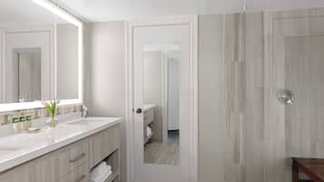A modern bathroom with a large mirror, a white sink, and a wooden vanity.