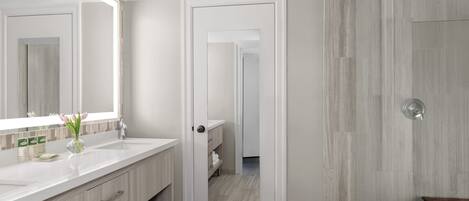Un baño moderno con un espejo grande, un lavabo blanco y un mueble de tocador de madera.