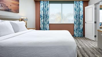 Una habitación de hotel con una cama grande, una ventana con cortinas, un cuadro en la pared y un armario.