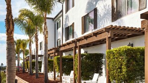 A multi-story building with a covered outdoor seating area and palm trees.