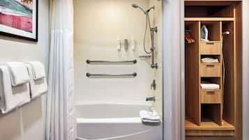 A modern bathroom with a walk-in shower, a bathtub, and a wooden storage closet.