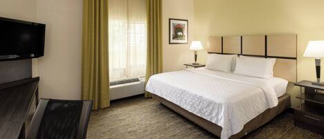 A hotel room with a bed, two bedside lamps, a TV, a desk, and a chair.