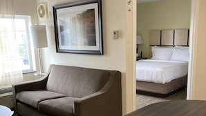 Une chambre d’hôtel avec un canapé, un lit, un bureau et un tableau encadré au mur.