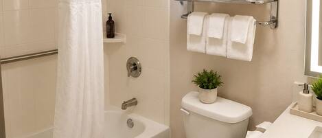 A bathroom with a bathtub, toilet, and a towel rack with towels.