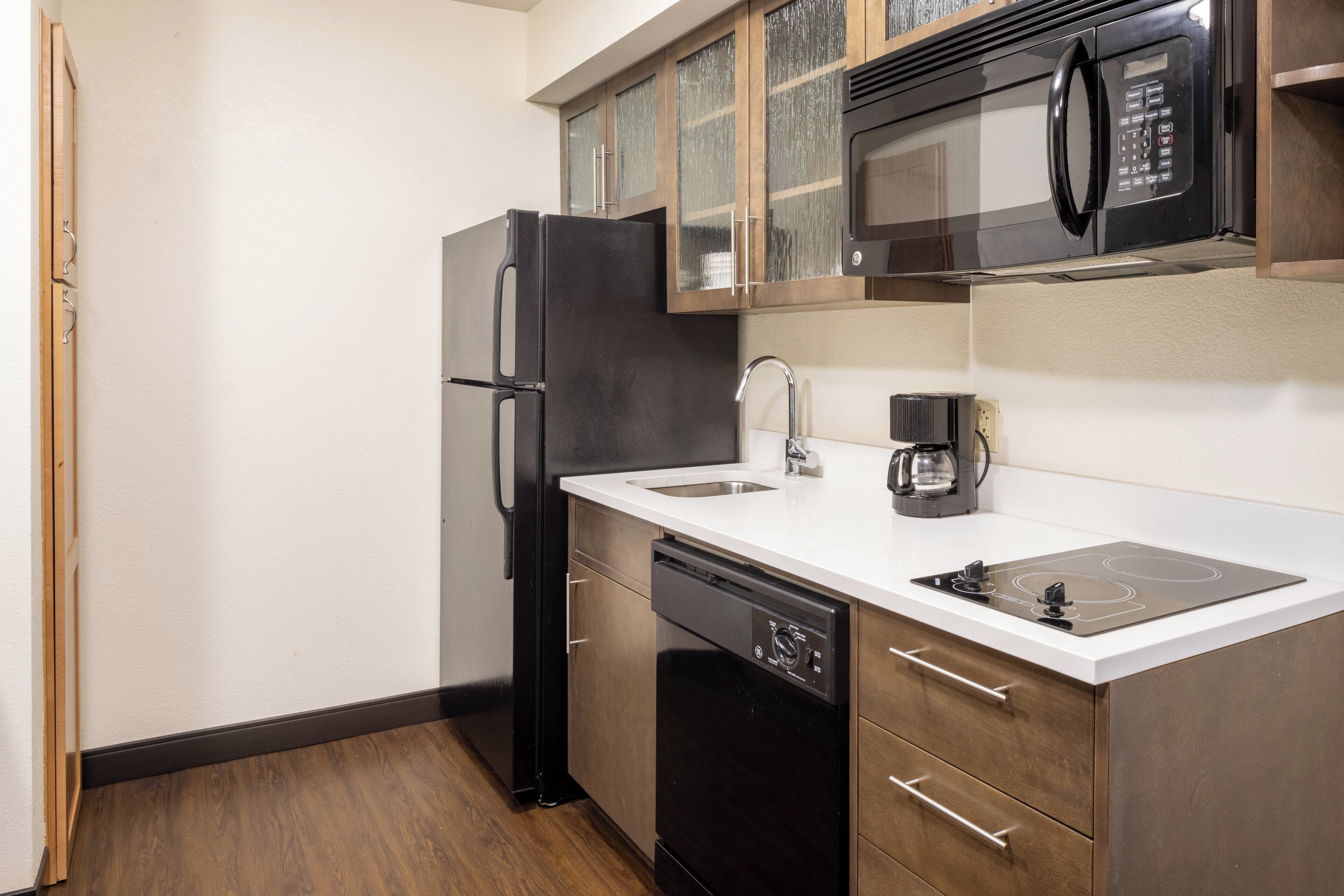 A compact kitchen with a refrigerator, microwave, dishwasher, and a coffee maker.