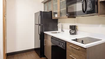 A compact kitchen with a refrigerator, microwave, dishwasher, and a coffee maker.