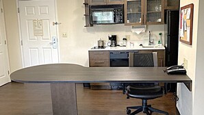 Una cocina con una isla grande, microondas, armarios y refrigerador.