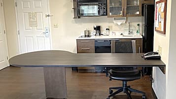 A kitchen with a large island, a microwave, cabinets, and a refrigerator.