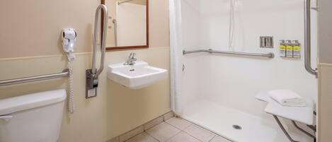 A bathroom with a toilet, sink, shower, and grab bars.
