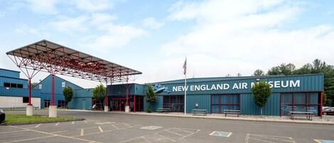 The exterior of the New England Air Museum with a large entrance canopy, parking lot, and American flag.