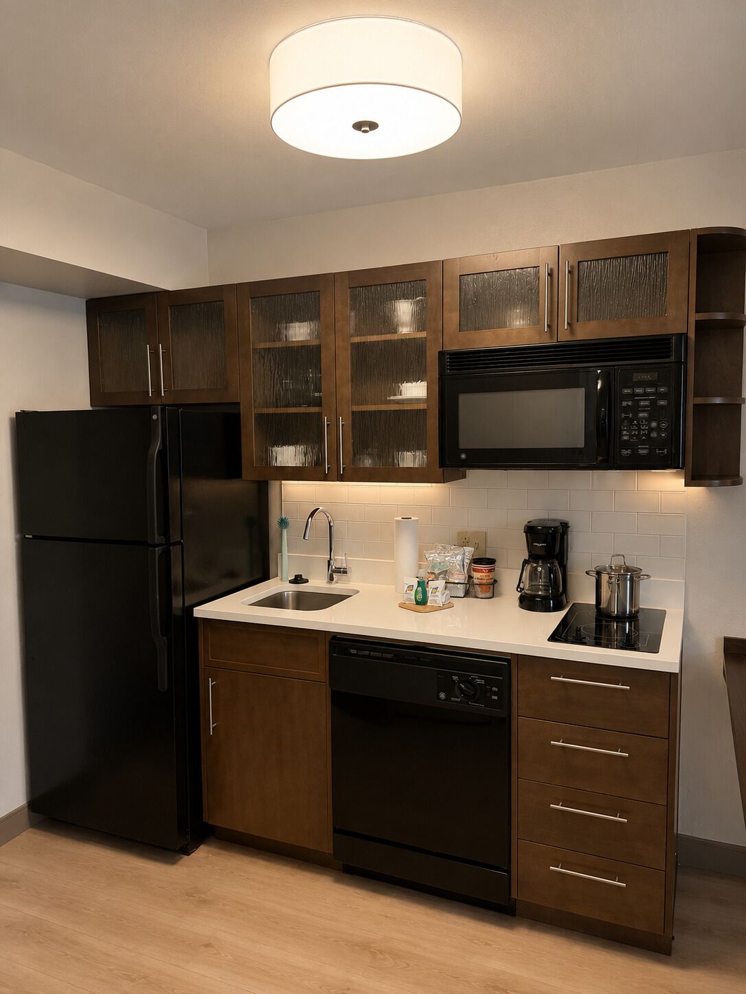 A modern kitchen with a black refrigerator, stainless steel microwave, and a dishwasher.