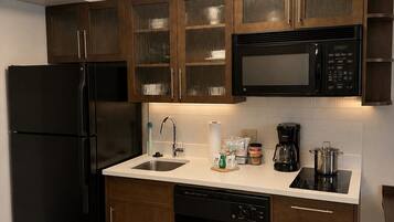 A modern kitchen with a black refrigerator, stainless steel microwave, and a dishwasher.