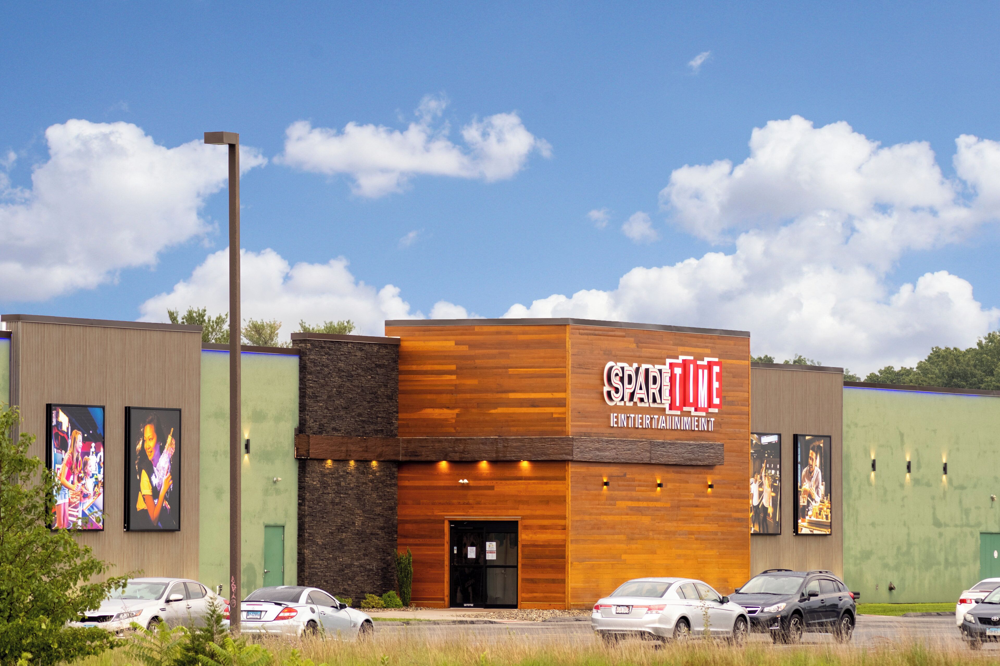 A building with a sign reading "SPARKTIME" and a parking lot with several cars.
