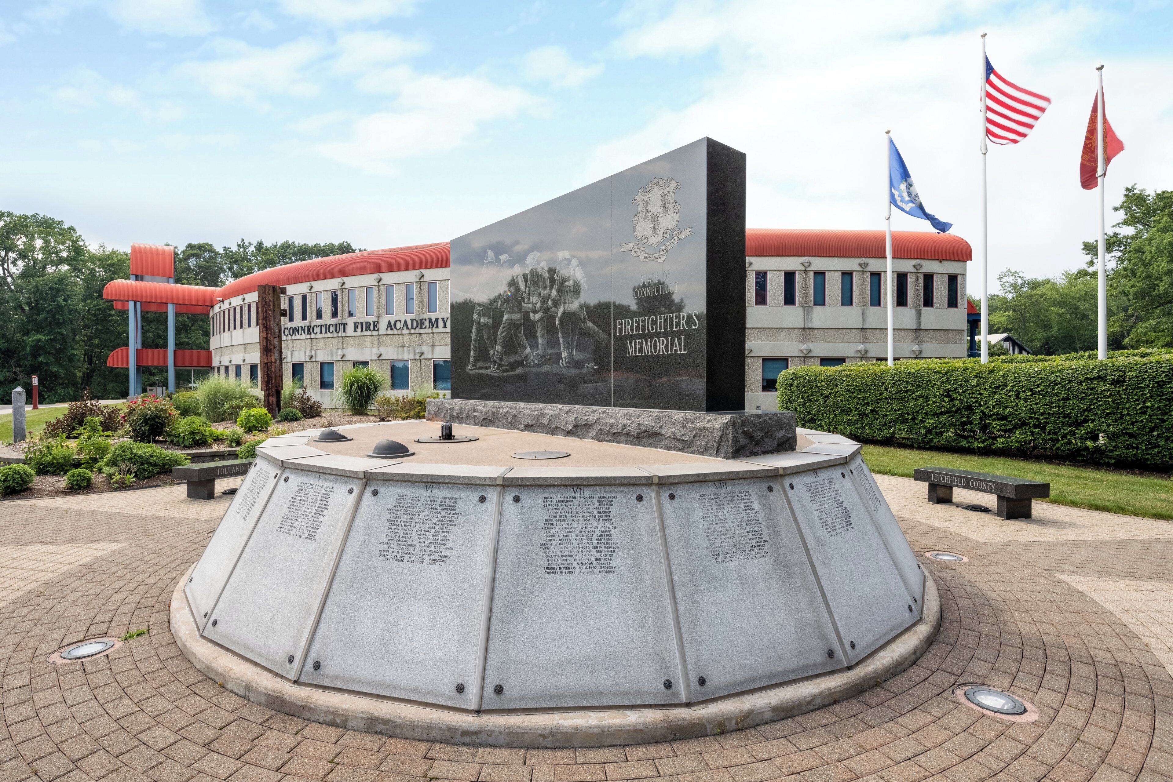 A memorial with inscriptions, a plaque, and a building labeled "Connecticut Fire Academy" in the background.